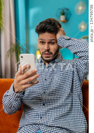 Sad Indian man use smartphone surprised by bad news, fortune loss, fail, lottery results, deadline Sad Indian man use smartphone surprised by bad news, fortune loss, fail, lottery results, deadline 134799786