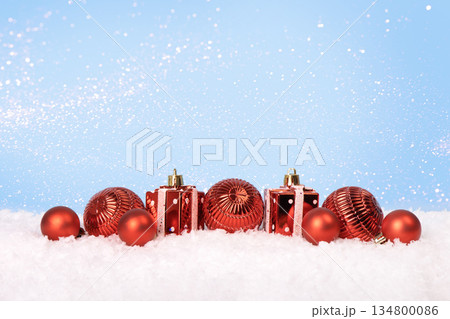 Christmas tree baubles on blue background with white snow and golden lights. Festive winter holiday background. Design with copy space for greeting card, text, advertising, banner, invitation 134800086