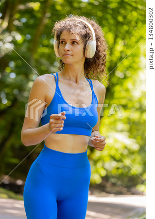 Athlete fit jogger girl running training marathon run listening music in wireless headphones in park 134800302