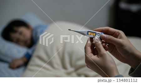 高熱を出して寝込む子どもの体温を計る様子とコピースペース 134801112