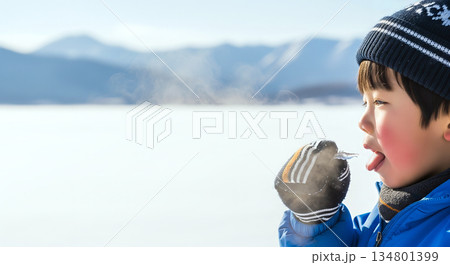つららを舐めて冬の寒さを体験する好奇心旺盛な男の子とコピースペース 134801399