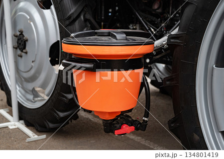 Close-up of an orange agricultural equipment component on a tractor wheel. Close-up of an orange agricultural equipment component on a tractor wheel. 134801419