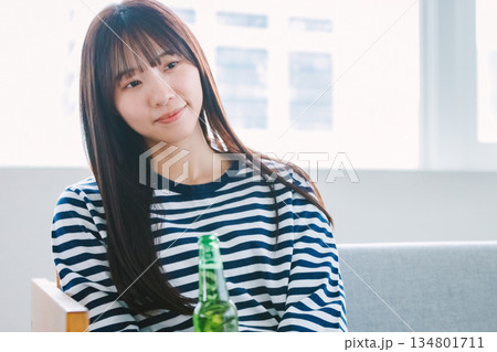 自宅のリビングでビールを飲む若い女性 自宅のリビングでビールを飲む若い女性 134801711