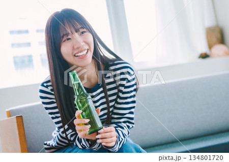 自宅のリビングでビールを飲む若い女性 134801720