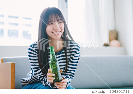 自宅のリビングでビールを飲む若い女性 自宅のリビングでビールを飲む若い女性 134801731