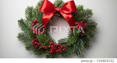 A lush evergreen Christmas wreath adorned with bright red berries and a satin red bow. A lush evergreen Christmas wreath adorned with bright red berries and a satin red bow. 134803232