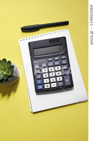 The calculator is on notebook on a yellow background The calculator is on notebook on a yellow background 134803869
