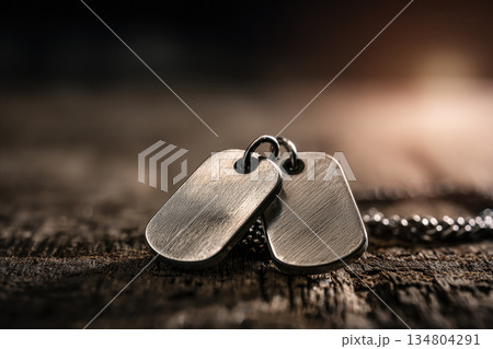 Dog tags rest on wooden background with soft light, symbolizing soldier identity and service, evoking sense of honor and remembrance 134804291