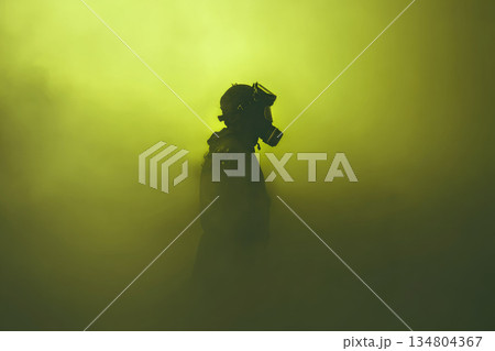 Cbrn soldier wearing gas mask stands in dense yellow fog, creating dramatic and intense atmosphere with protective gear and military uniform 134804367