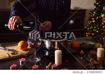 Elegant Winter Dinner Scene With Woman Pouring Red Wine Beside Candles And Christmas Tree 134804843