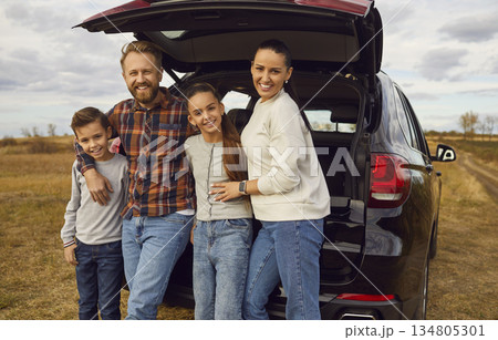 Happy smiling family with children looking at camera near the trunk of car enjoying weekend. Happy smiling family with children looking at camera near the trunk of car enjoying weekend. 134805301
