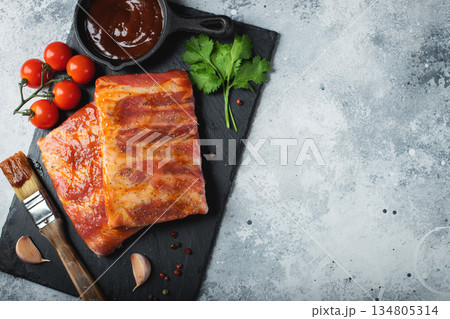 Ready for BBQ raw pork spare ribs with barbecue sauce. Black background. Top view 134805314