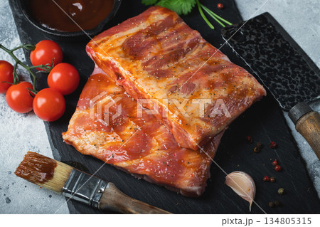 Ready for BBQ raw pork spare ribs with barbecue sauce. Black background. Top view 134805315