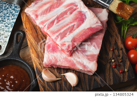 Raw pork ribs with spices, salt and rosemary on dark wooden background Raw pork ribs with spices, salt and rosemary on dark wooden background 134805324