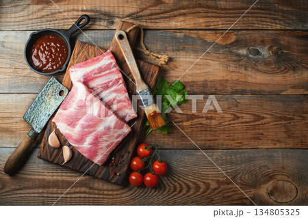 Raw pork ribs with spices, salt and rosemary on dark wooden background Raw pork ribs with spices, salt and rosemary on dark wooden background 134805325