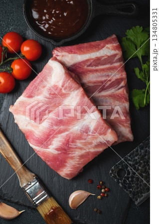 Raw meat. Raw pork ribs from the back with meat on a black background. background image 134805331