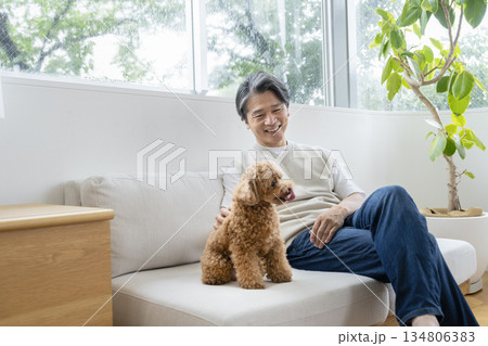 ソファでくつろぐ50代の男性と犬　犬との暮らしイメージ 134806383