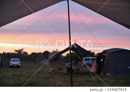 夕焼け空とキャンプサイト　タープ越しのテント風景 134807633