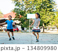 Two young girls playing basketball together on outdoor court 134809980
