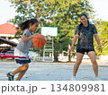 Mother and daughter played basketball together on an outdoor court during sunset. 134809981