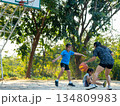Happy Asian family playing basketball together on outdoor court at the park during golden hour. 134809983