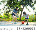 Mother and daughter played basketball together on an outdoor court during sunset. 134809993