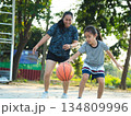 Mother and daughter played basketball together on an outdoor court during sunset. 134809996