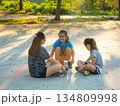 Asian mother and daughters sitting on court, resting and talking after playing basketball. 134809998