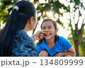 Affectionate Asian mother playing and pinching her daughter's cheek with love. 134809999