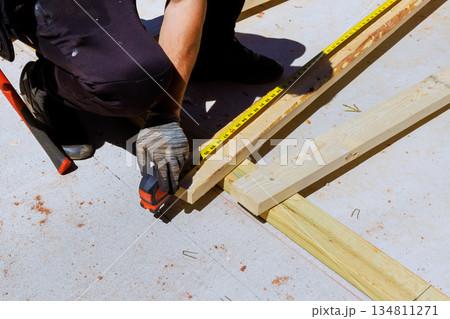 Worker is measuring wooden beams boards with tape measure on construction site 134811271