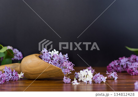 Lilac in a wooden scoop on a black background 134812428