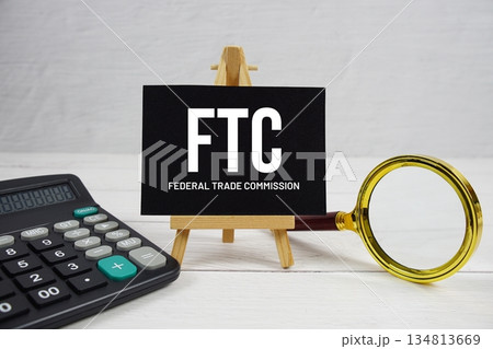 FTC abbreviation of Federal Trade Commission text with magnifying glass and calculator on wooden background FTC abbreviation of Federal Trade Commission text with magnifying glass and calculator on wooden background 134813669