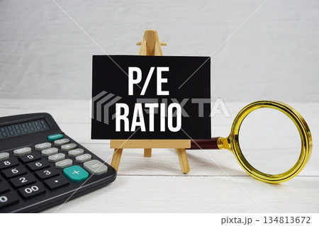 P/E abbreviation of Ratio acronyms Price-To-Earnings text with magnifying glass and calculator on wooden background 134813672