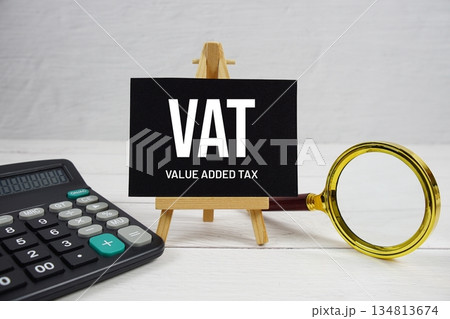 VAT abbreviation of Value Added Tax text with magnifying glass and calculator on wooden background VAT abbreviation of Value Added Tax text with magnifying glass and calculator on wooden background 134813674