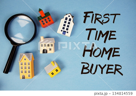 First Time Home Buyer text with house models and magnifying glass on blue background First Time Home Buyer text with house models and magnifying glass on blue background 134814559