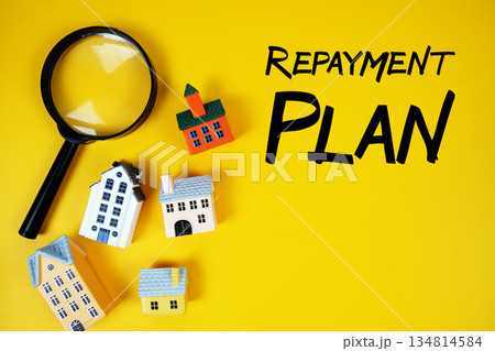 Repayment Plan text with house models and magnifying glass on yellow background Repayment Plan text with house models and magnifying glass on yellow background 134814584