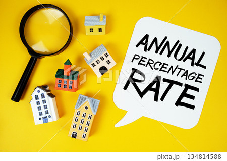APR Annual Percentage Rate text with house models and magnifying glass on yellow background 134814588
