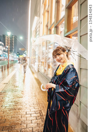 雨の日の夜に街中で傘をさして立っている着物姿の若い女性 雨の日の夜に街中で傘をさして立っている着物姿の若い女性 134814843