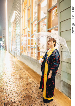 雨の日の夜に街中で傘をさして立っている着物姿の若い女性 134814850