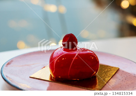 Refined cafe setting showcasing glossy raspberry mousse with reflective light effects Refined cafe setting showcasing glossy raspberry mousse with reflective light effects 134815334