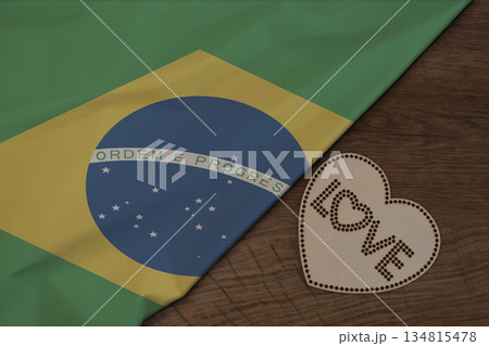 Brazilian flag fabric on wooden surface and word LOVE on wooden heart patriotic postcard design 134815478