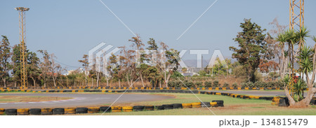 Outdoor go-kart racing track lined with black and yellow painted tires under a clear blue summer sky 134815479