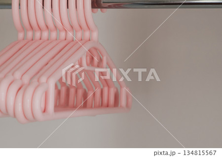Plastic soft pink hangers for children's clothes in the wardrobe 134815567