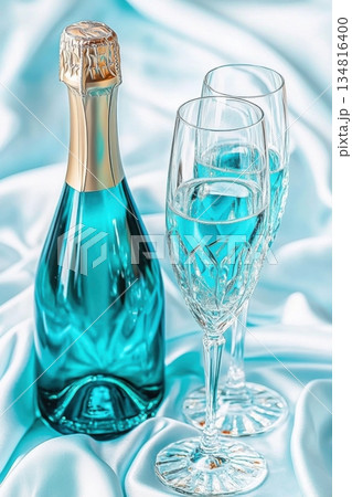 Luxurious turquoise sparkling wine with crystal glasses set on silky white fabric for elegant celebrations 134816400