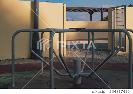 Empty children's swing set on a playground with a ground covering in a park Empty children's swing set on a playground with a ground covering in a park 134817430
