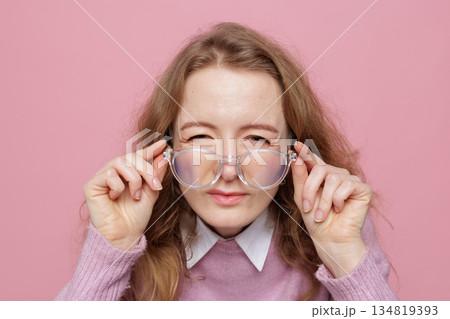 Close up portrait of woman with prescription glasses showing eye strain and poor focus from screen fatigue 134819393