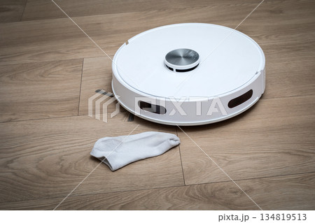 Smart Robotic Vacuum Cleaner Approaching Fabric Obstacle On Modern Wooden Floor 134819513