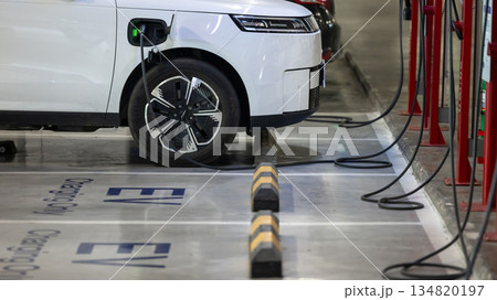EV charging and electric car, Electric car charging station for charge EV battery, Plug for vehicle with electric engine, EV charger clean energy, Charging point at car parking lot 134820197