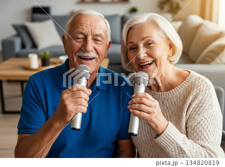 Elderly man and woman singing karaoke together in a cozy modern living room 134820819