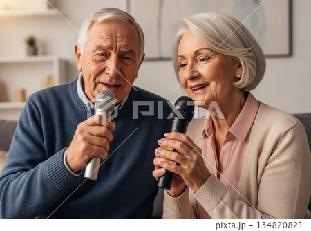 Elderly man and woman singing karaoke together in a cozy modern living room 134820821
